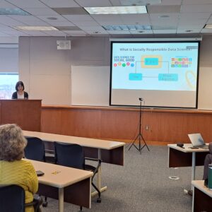 Dr. Chen in front of podium to the left and slides projected on screen to right that says "What is Socially Responsible Data Science"